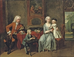 A family portrait of a gentleman, his wife handing an apple to the daughter and their son feeding a parrot, all in an interior, a park beyond by Cornelis Troost