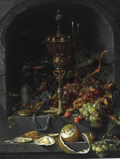 Still life of fruit and a chalice in a niche by Abraham Mignon