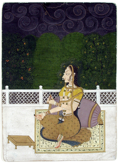 A beautiful woman seated against a bolster