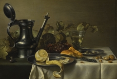 Still life with a 'Jan Steen' jug, a peeled lemon on a pewter plate, bread, a knife, olives on a pewter plate, grapes, a glass and nuts by Pieter Claesz