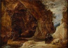 Hermit sitting on a rock next to the entrance of a grotto