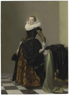 Portrait of a richly dressed young lady, full-length, before a draped table